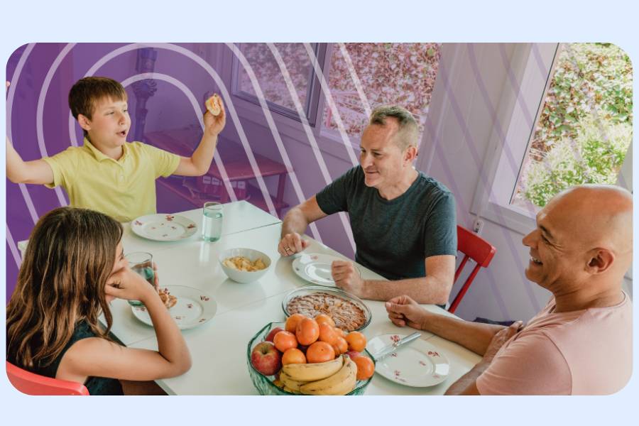 Two parents and two teenagers eating and laughing at the kitchen table